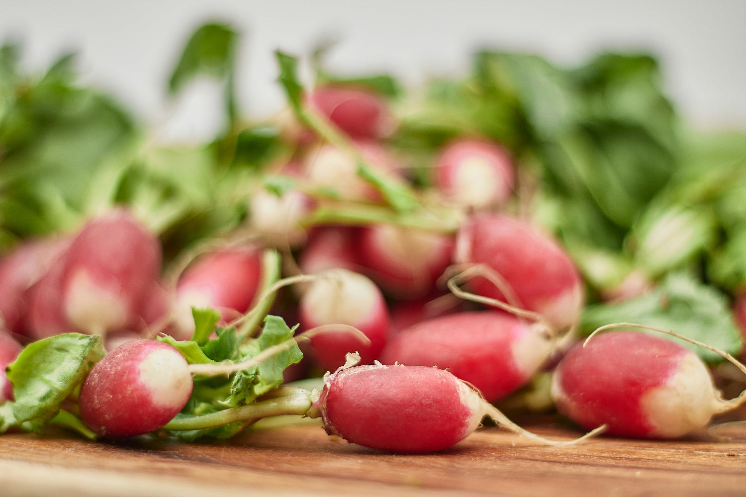 Fresh radishes with green leaves on a wooden surface